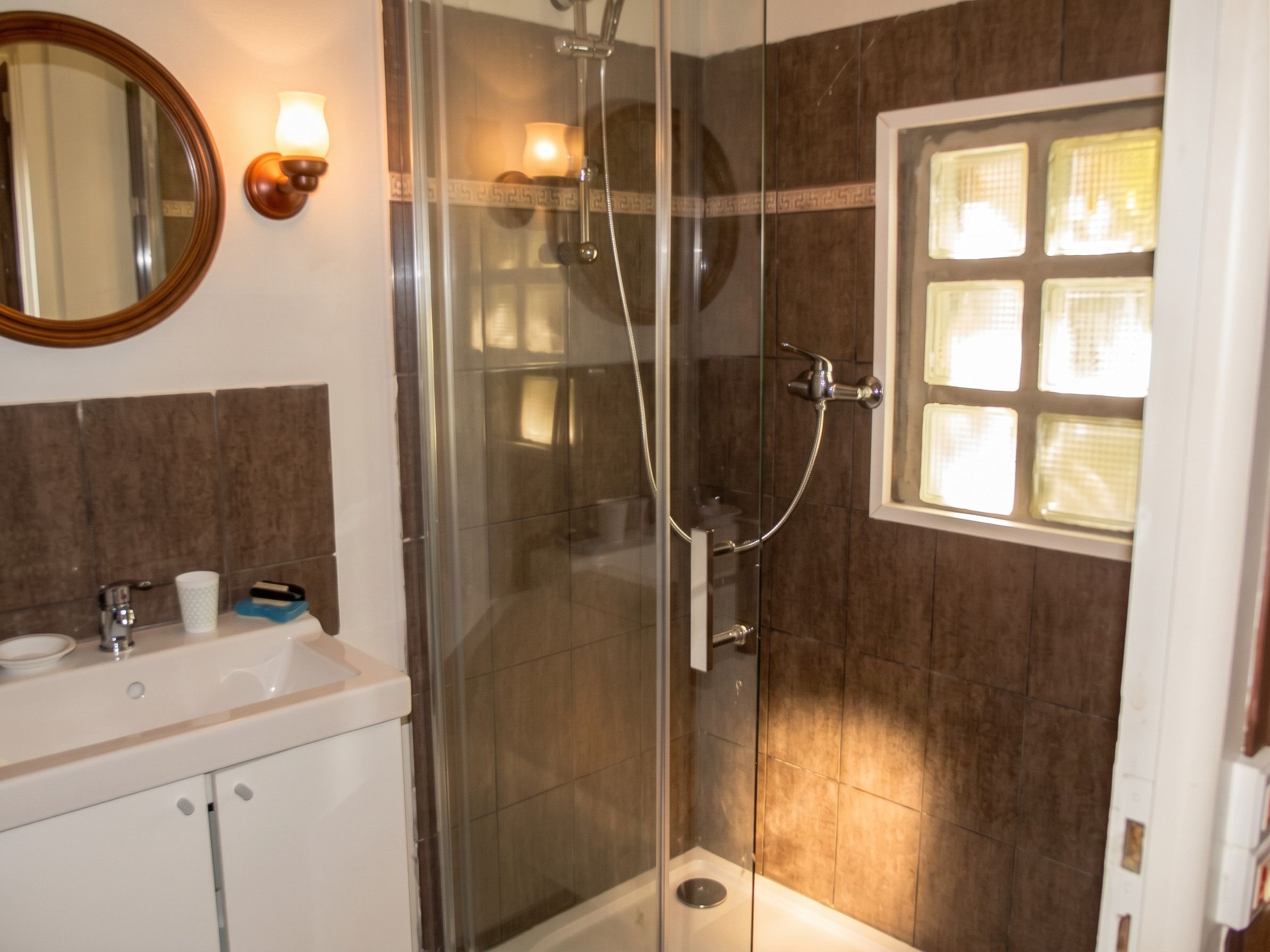 Ein Badezimmer mit einer Duschkabine, einem Waschbecken und einem Spiegel.