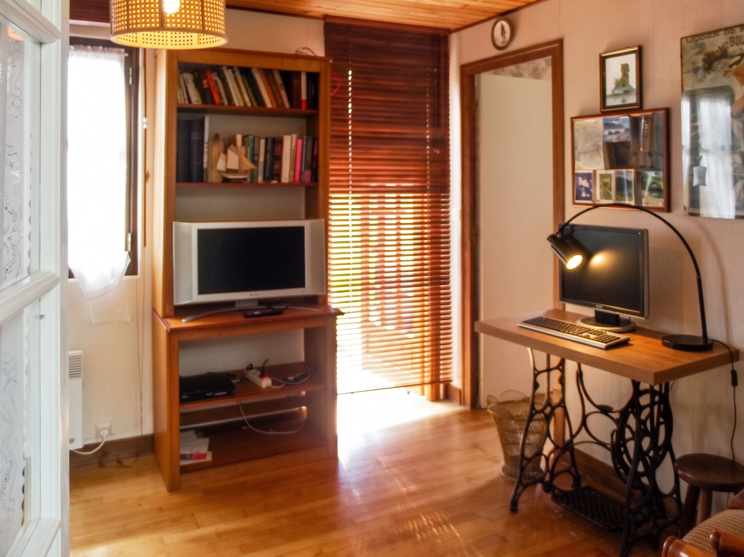 Une pièce avec un bureau en bois, une télévision et une bibliothèque.