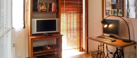 Ein Zimmer mit einem Holztisch, einem Fernseher und einem Bücherregal.