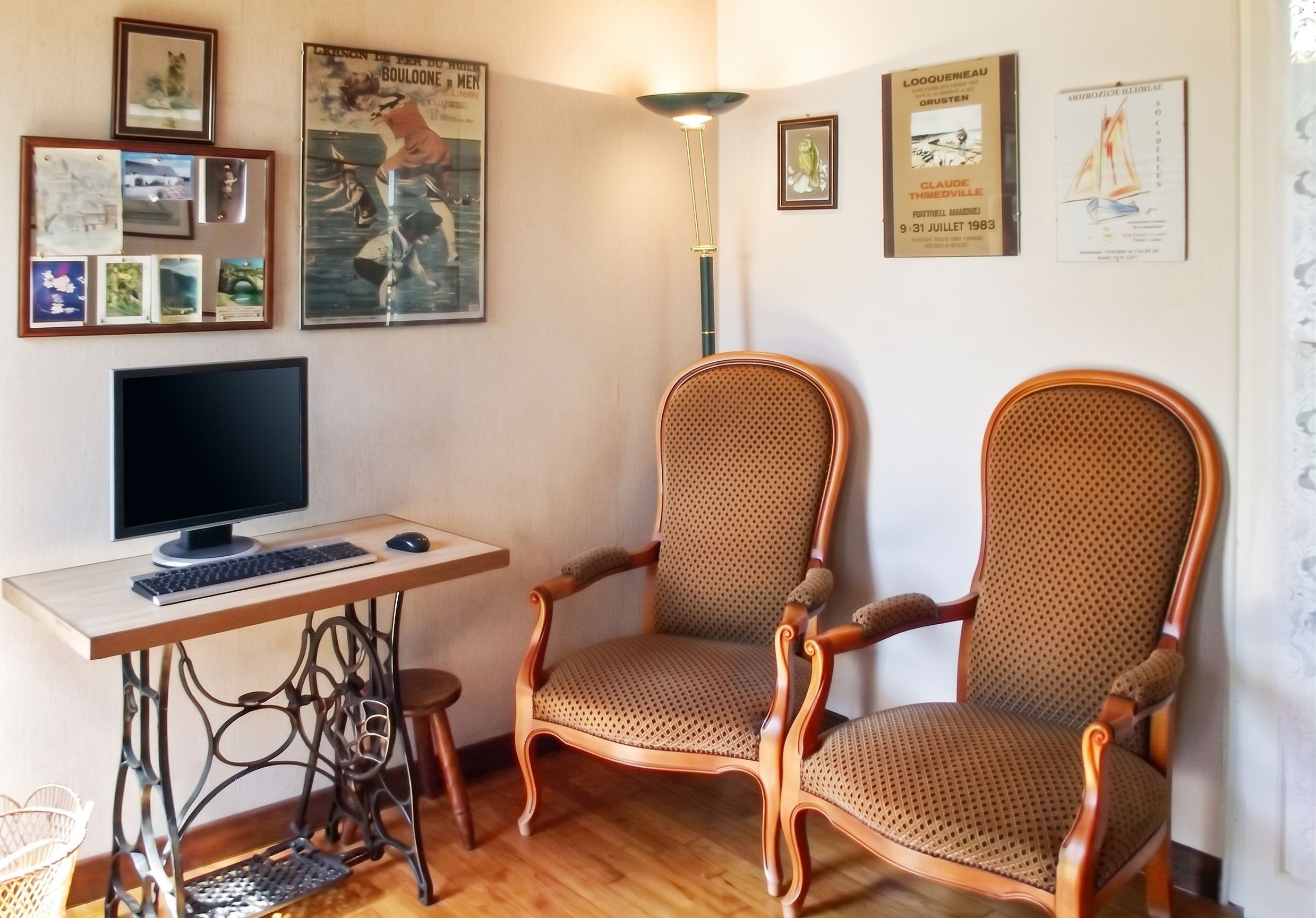 Une pièce comprenant un bureau, un ordinateur, deux chaises et divers tableaux encadrés accrochés au mur.