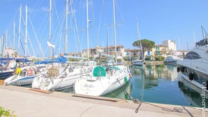 Un port de plaisance où sont amarrés de nombreux voiliers, un ciel dégagé et des bâtiments en arrière-plan.