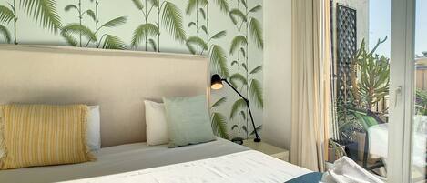 A hotel room with a bed, pillows, a lamp, and a view of the outside.