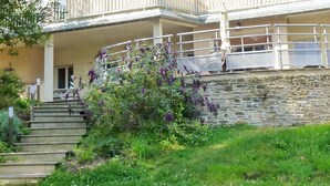 A building with a stone wall and a staircase leading to a porch. - Ground floor apartment with terraces, WIFI, parking, and pets allowed (Barneville-Carteret)