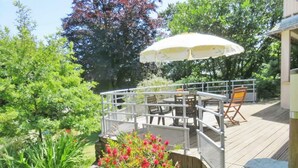 An outdoor deck with a table and chairs, surrounded by greenery and a white umbrella. - Ground floor apartment with terraces, WIFI, parking, and pets allowed (Barneville-Carteret)
