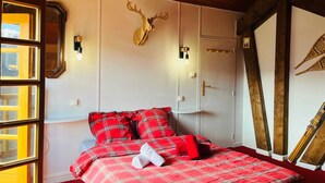Une chambre à coucher avec une couvre-lit à carreaux, une tête de cerf fixée au mur et un plafond en bois.