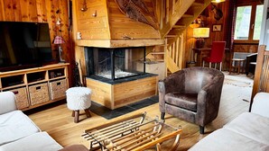Un intérieur de chalet chaleureux avec une cheminée, des meubles en bois et un téléviseur.
