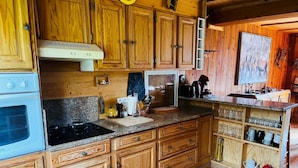 Une cuisine en bois avec des placards intégrés, une cuisinière et un four à micro-ondes.