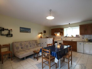 A compact living space with a dining area, kitchenette, and a sofa. - Charming Beachside Home with Terrace, BBQ, and Baby Equipment in Hauteville-sur-Mer (Hauteville-sur-Mer)