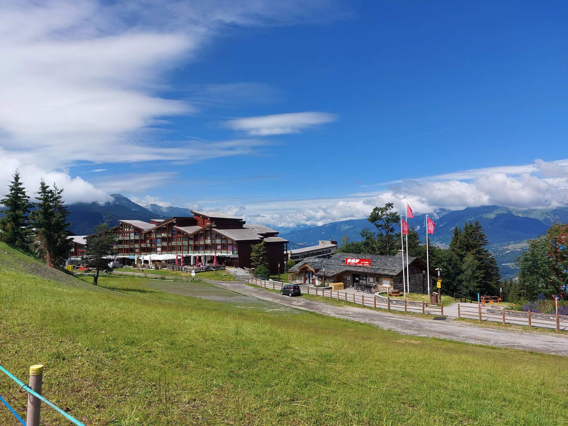 A hotel with multiple buildings, a parking area, and a view of mountains.