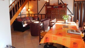Ein gemütliches Wohnzimmer mit einer Holztreppe, einem Essbereich mit Tisch und einer Ziegelwand.