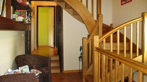 Ein Wohnzimmer mit einem braunen Sofa, einer Holztreppe und einem Bücherregal.