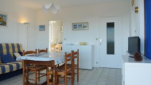 A compact living space with a dining area, a sofa, a TV, and a small kitchenette. - Renovated 1BR with balcony, covered parking, pets allowed (Les Sables-d'Olonne)