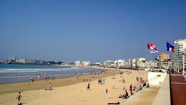 A beach with people, a clear sky, and buildings in the background. - Renovated 1BR with balcony, covered parking, pets allowed (Les Sables-d'Olonne)