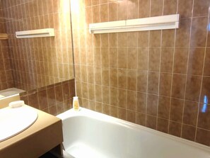 Un bagno con una vasca, un lavandino e uno specchio.