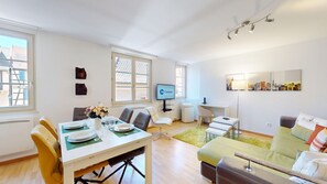 Un salon moderne comprenant un coin repas, un téléviseur et des œuvres d’art accrochées aux murs.