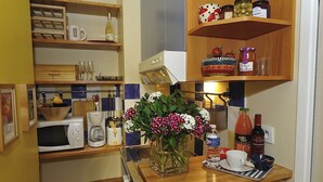 A compact kitchen with a microwave, toaster, coffee maker, and a vase of flowers on the counter. - A1DG Home Sweet home (París)
