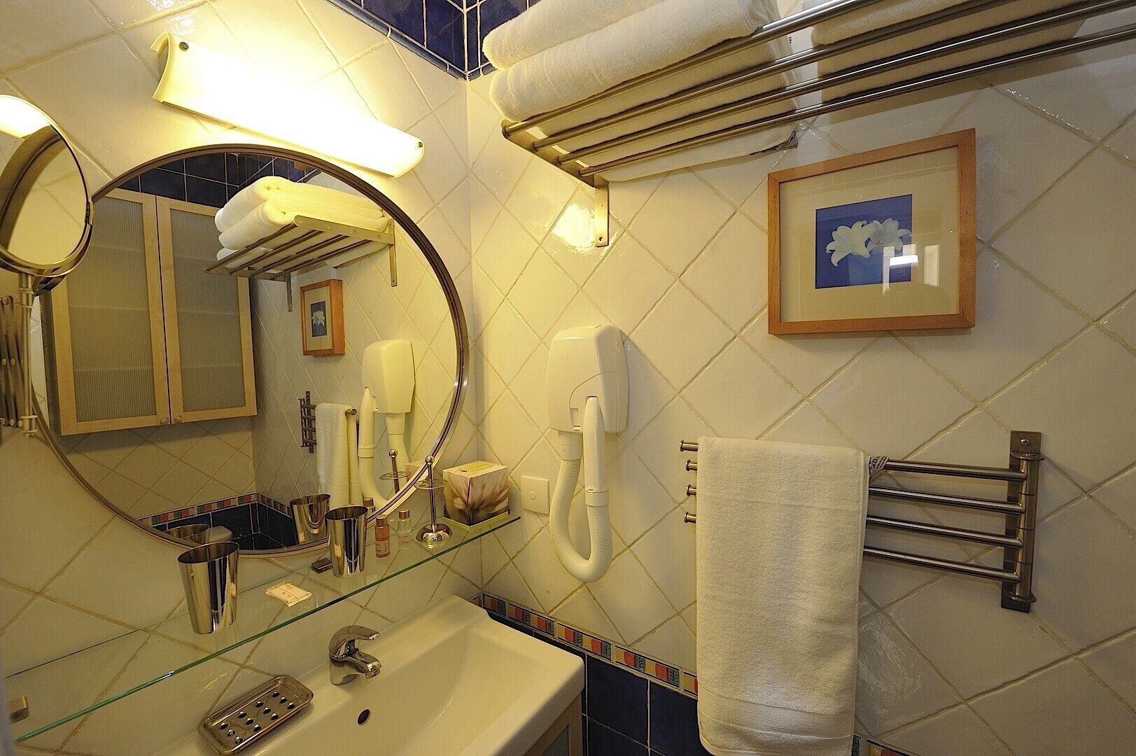 A bathroom with a sink, mirror, towel rack, and a framed picture on the wall.