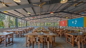 A spacious outdoor dining area with multiple tables and chairs, ceiling fans, and hanging pendant lights. - Nature Trails Sajan, Vikramgad (Vikramgadh)