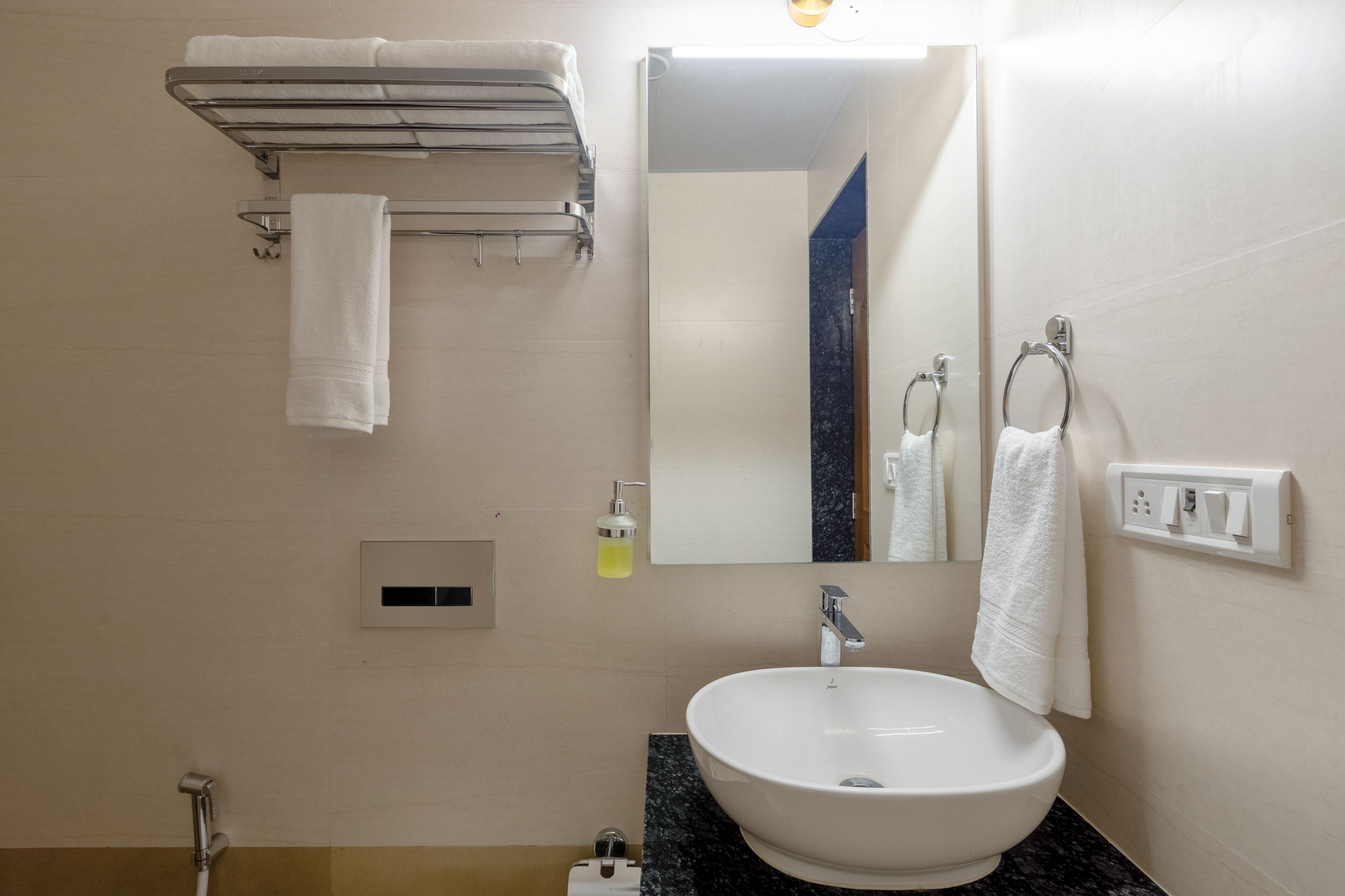 Une salle de bain équipée d’un lavabo, d’un miroir, d’un porte-serviettes et d’un distributeur de savon.