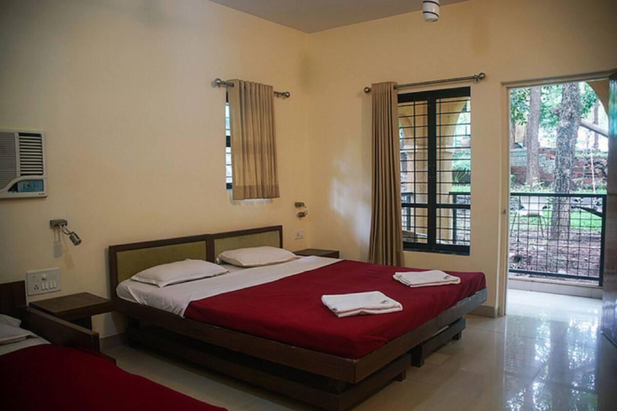 Quarto de hotel com cama, mesa de cabeceira, janela com cortinas e vista para o exterior.