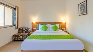 A neatly made bed with a green quilt, two pillows, and a bedside table with a lamp. - Nature Trails Sajan, Vikramgad (Vikramgadh)