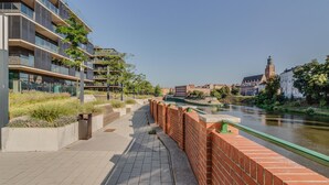 Un paseo fluvial con edificios modernos, un muro de ladrillo y un puente.