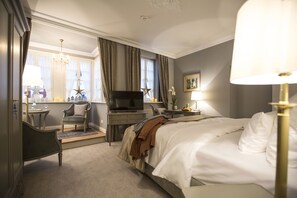 Una habitación de hotel con cama, escritorio, televisor, silla y ventana con cortinas.