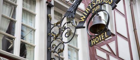 Un letrero de hotel con el nombre 'Wirtshaus Zur' y una campana.