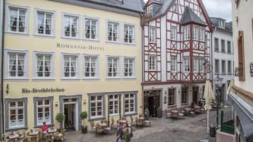 A hotel with a traditional European facade, outdoor seating, and a cobblestone courtyard.