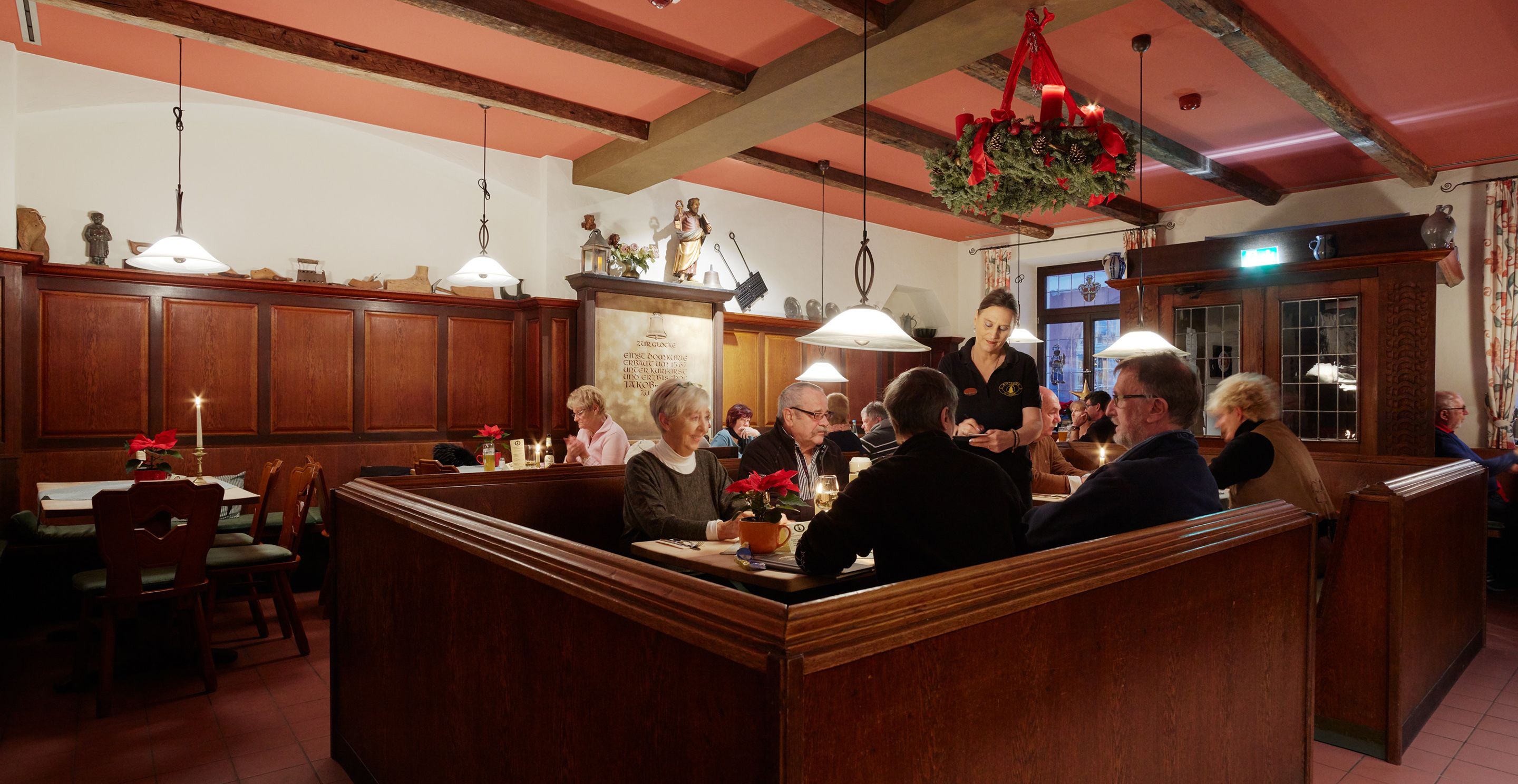 A restaurant with wooden booths, a bar area, and a Christmas decoration.