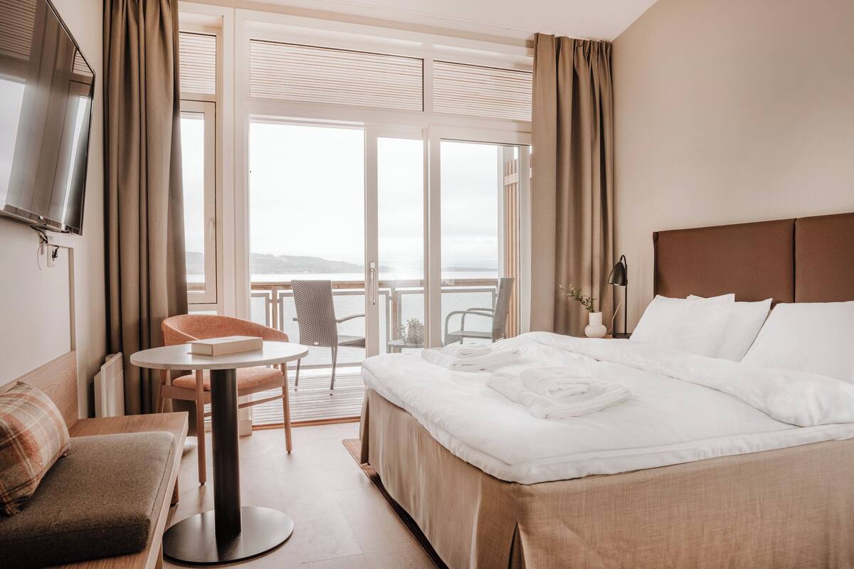 Habitación de hotel con una cama grande, un sofá, una mesa redonda y una televisión.