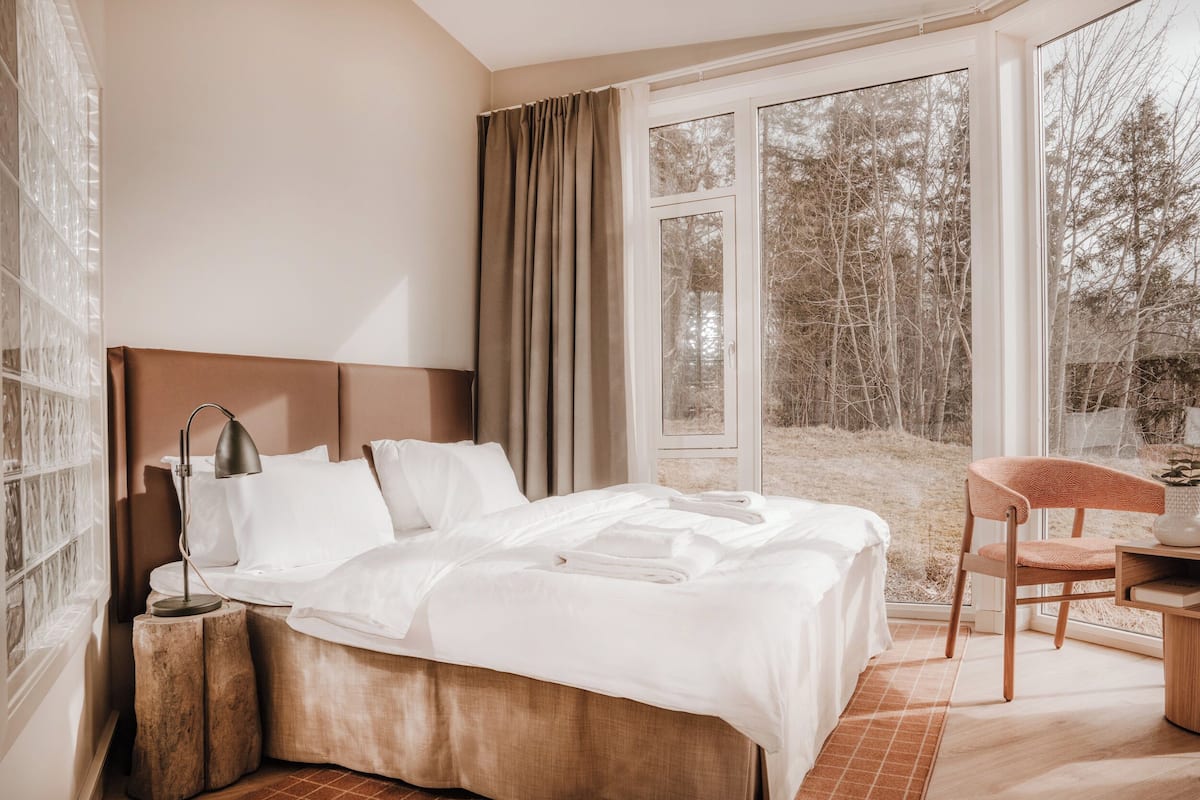 Habitación de hotel con una cama grande, un escritorio con una silla y vistas a árboles a través de la ventana.