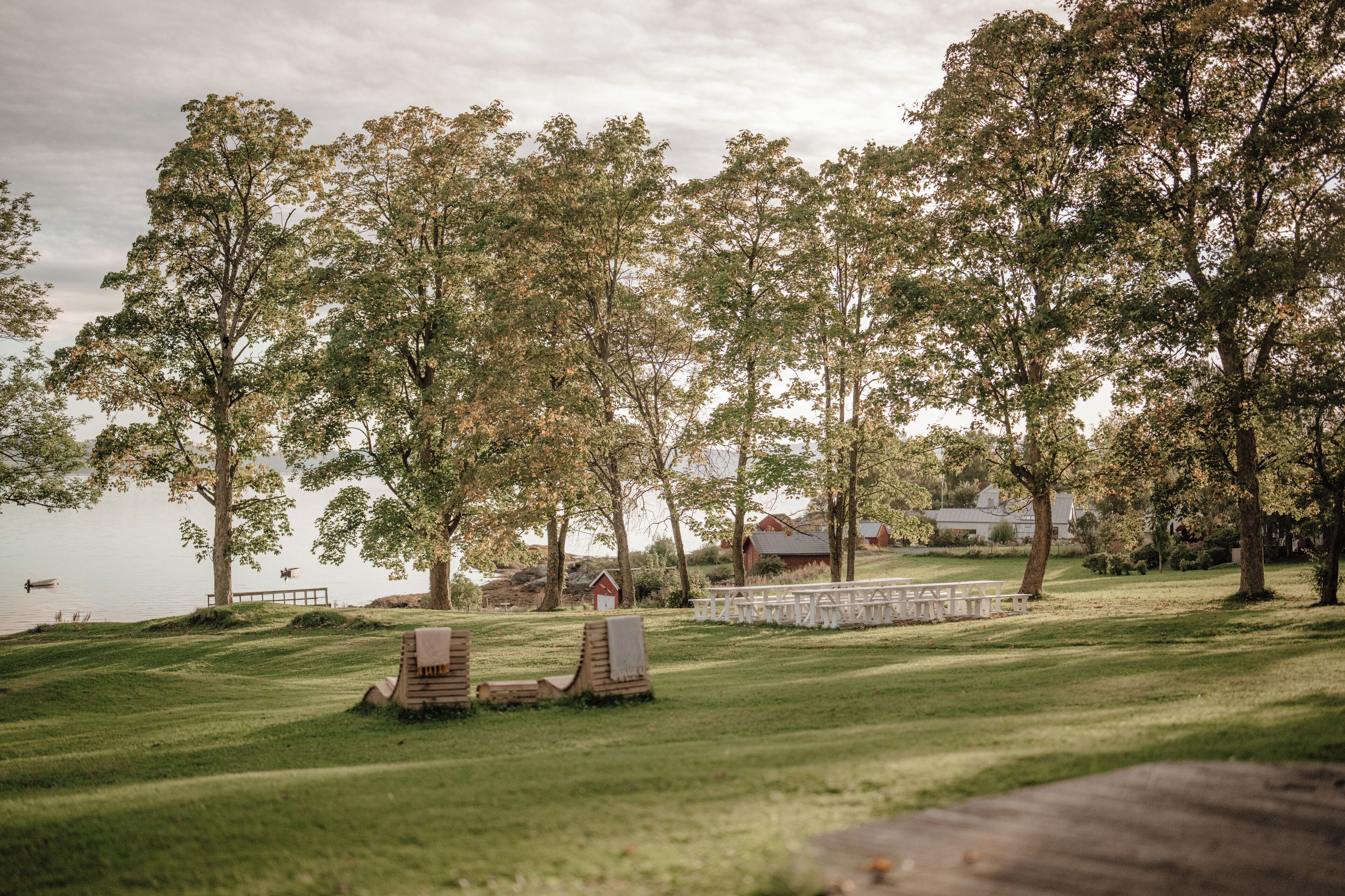 A grassy outdoor area with wooden benches and a white fence.