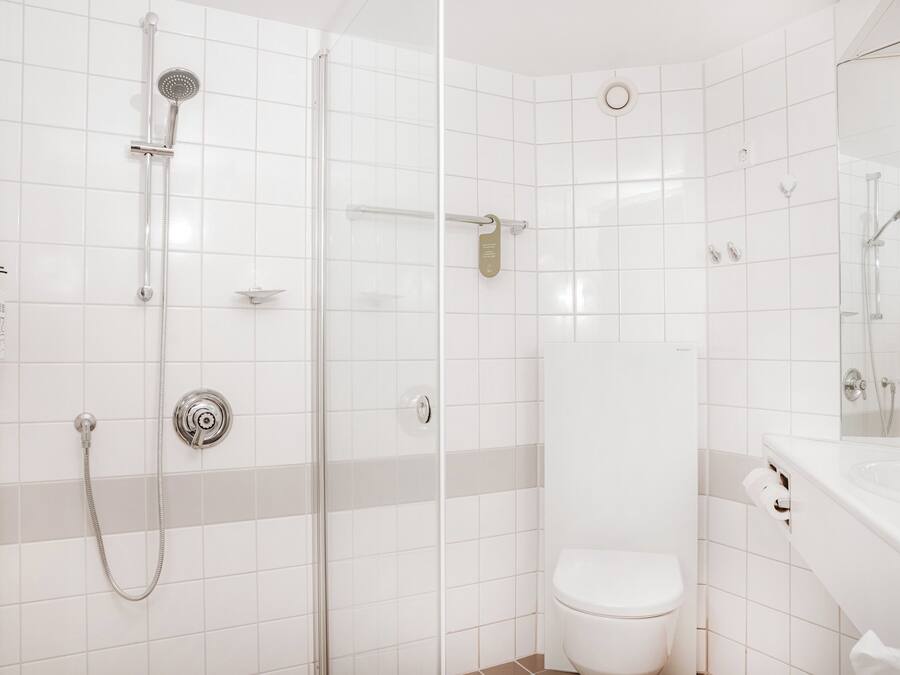 A modern bathroom with a glass-enclosed shower, a toilet, and a sink with a mirror.