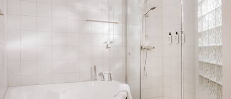 Un baño moderno con una bañera grande, ducha con mampara de vidrio y un perchero para toallas.