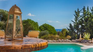 A poolside area with a wooden deck, a lantern, and a chair. - Driftwood Villa (Kefalonia)