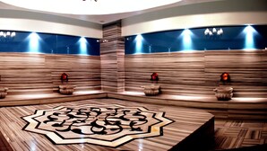 A modern spa area with a central seating area, wall-mounted massage chairs, and a decorative floor pattern. - Alba Ankara Hotel (Ankara)