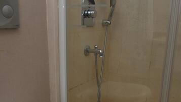 Ein Badezimmer mit Toilette, einer Duschkabine und einer an der Wand befestigten Bedienkonsole.