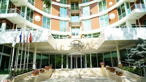 A modern hotel entrance with a central glass door, multiple balconies, and potted plants. - Alba Ankara Hotel (Ankara)