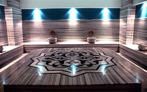 Un baño con un amplio diseño ornamental en el suelo, dos lavamanos con grifos e iluminación empotrada.