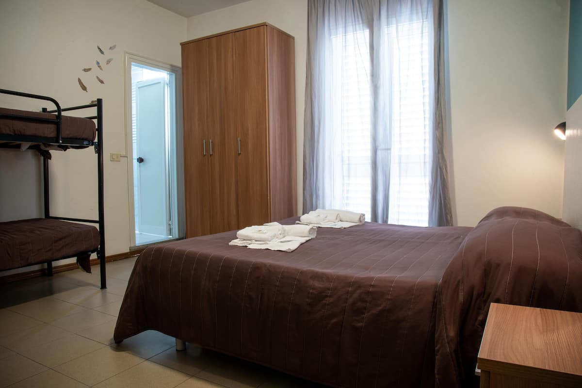 A bedroom with a bunk bed, a wardrobe, and a bed with towels.