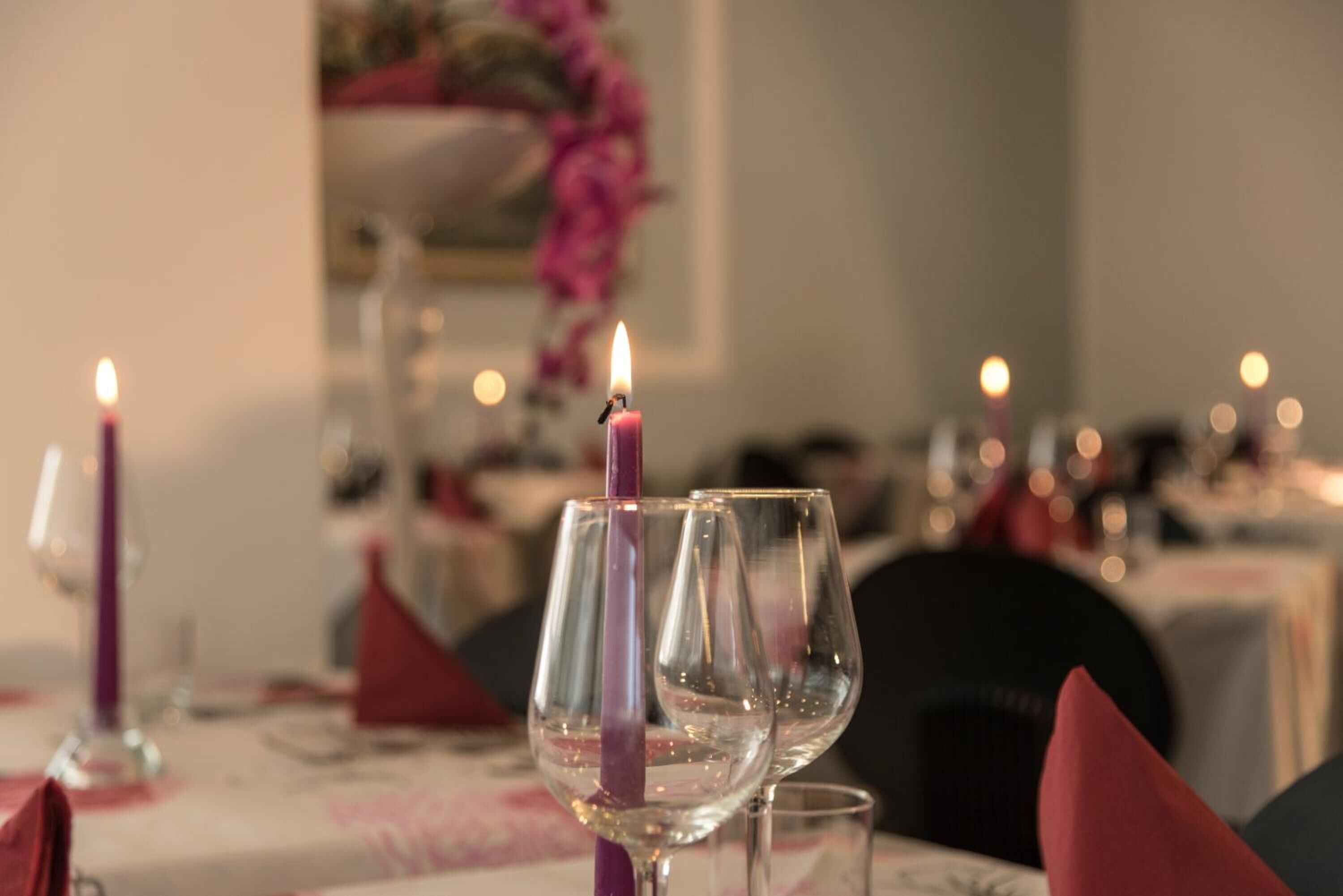 A dining table with empty wine glasses and a lit candle.
