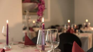 A dining table with empty wine glasses and a lit candle.
