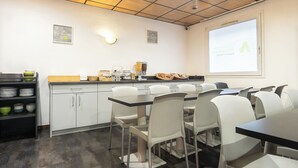 Une cuisine moderne avec des meubles blancs, un plan de travail noir et un grand écran diffusant une présentation.