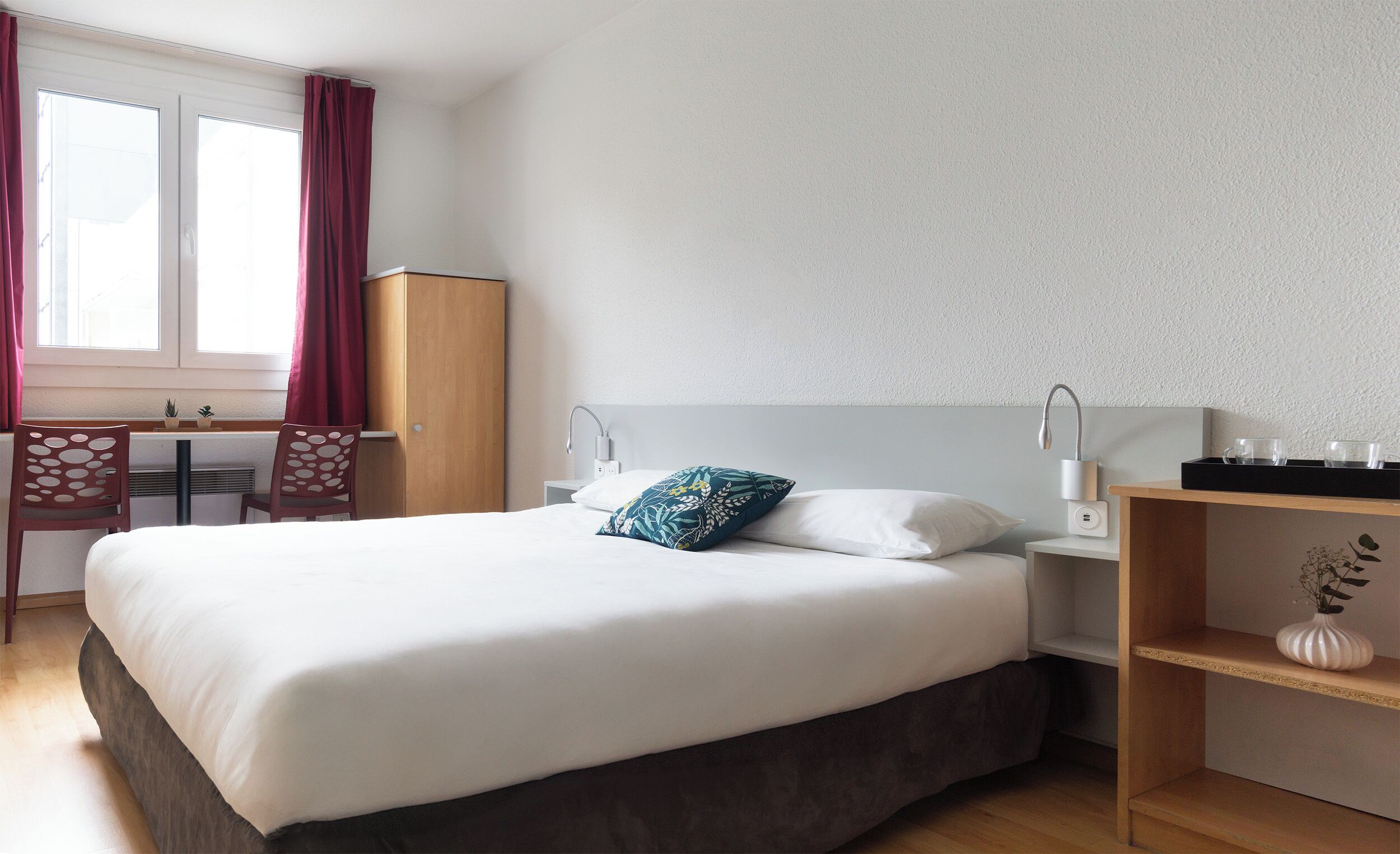 Habitación de hotel ordenada con cama, escritorio y una silla.