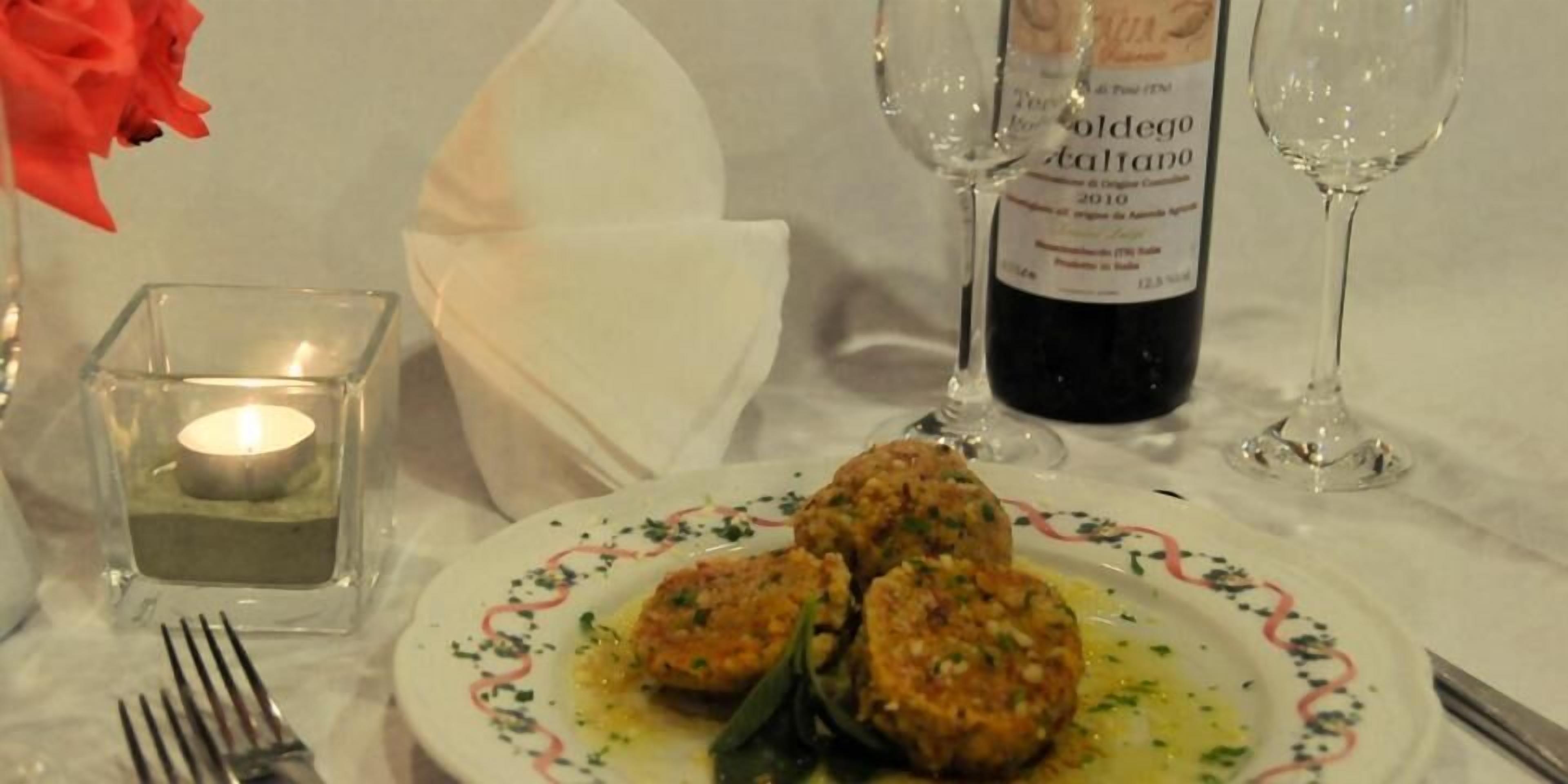 Un tavolo da pranzo con un piatto di cibo, una bottiglia di vino e dei bicchieri.