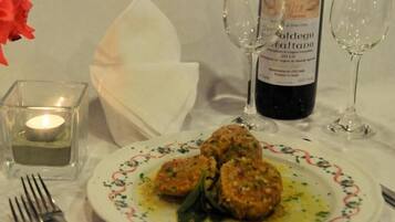 Un tavolo da pranzo con un piatto di cibo, una bottiglia di vino e dei bicchieri.