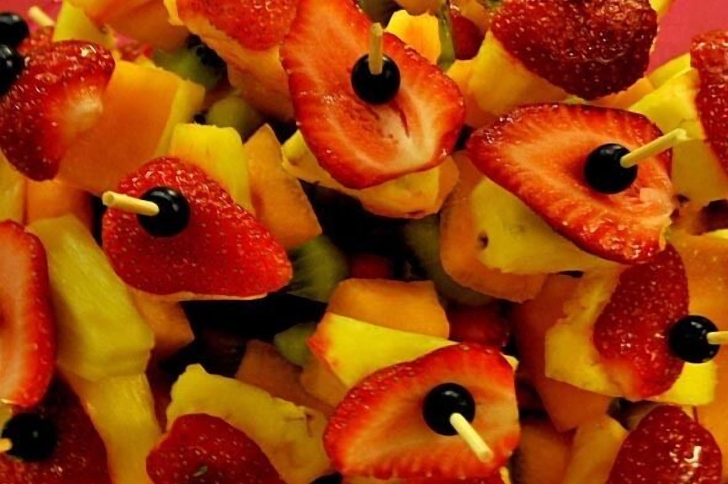 A close-up of fruit skewers with strawberries and pineapple chunks.