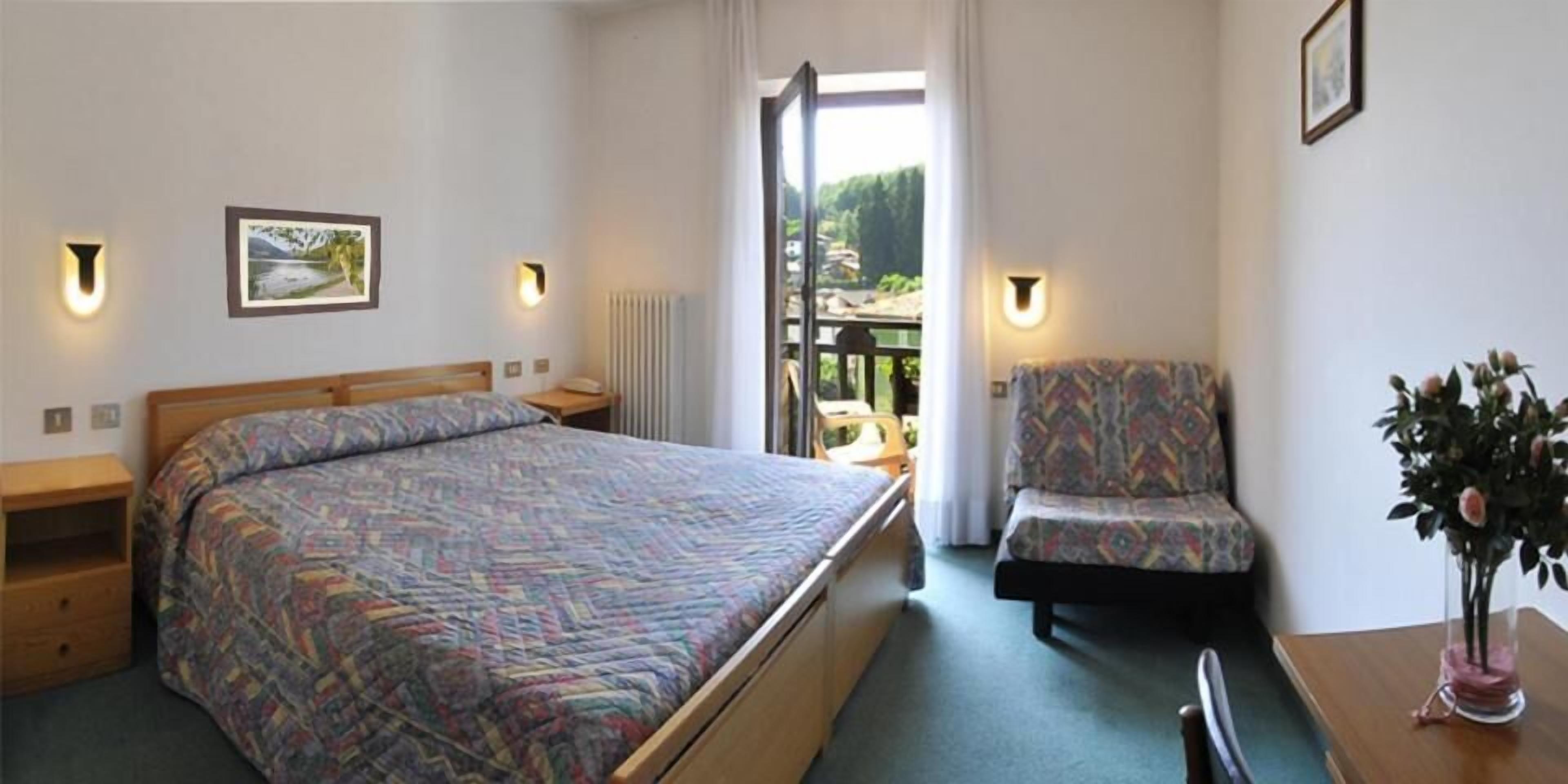 Ein Hotelzimmer mit Bett, Sessel, kleinem Tisch und Blick ins Freie.