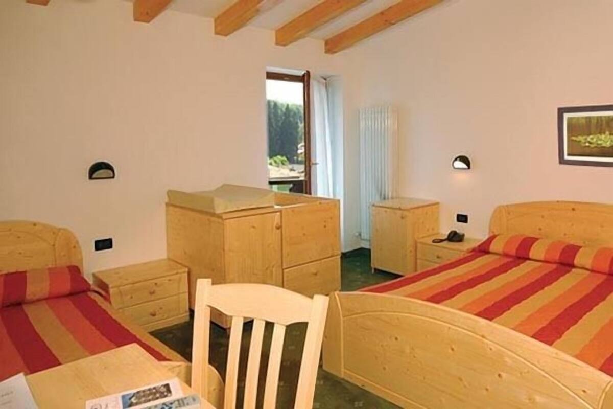 A bedroom with two beds, wooden furniture, and a window with a view.